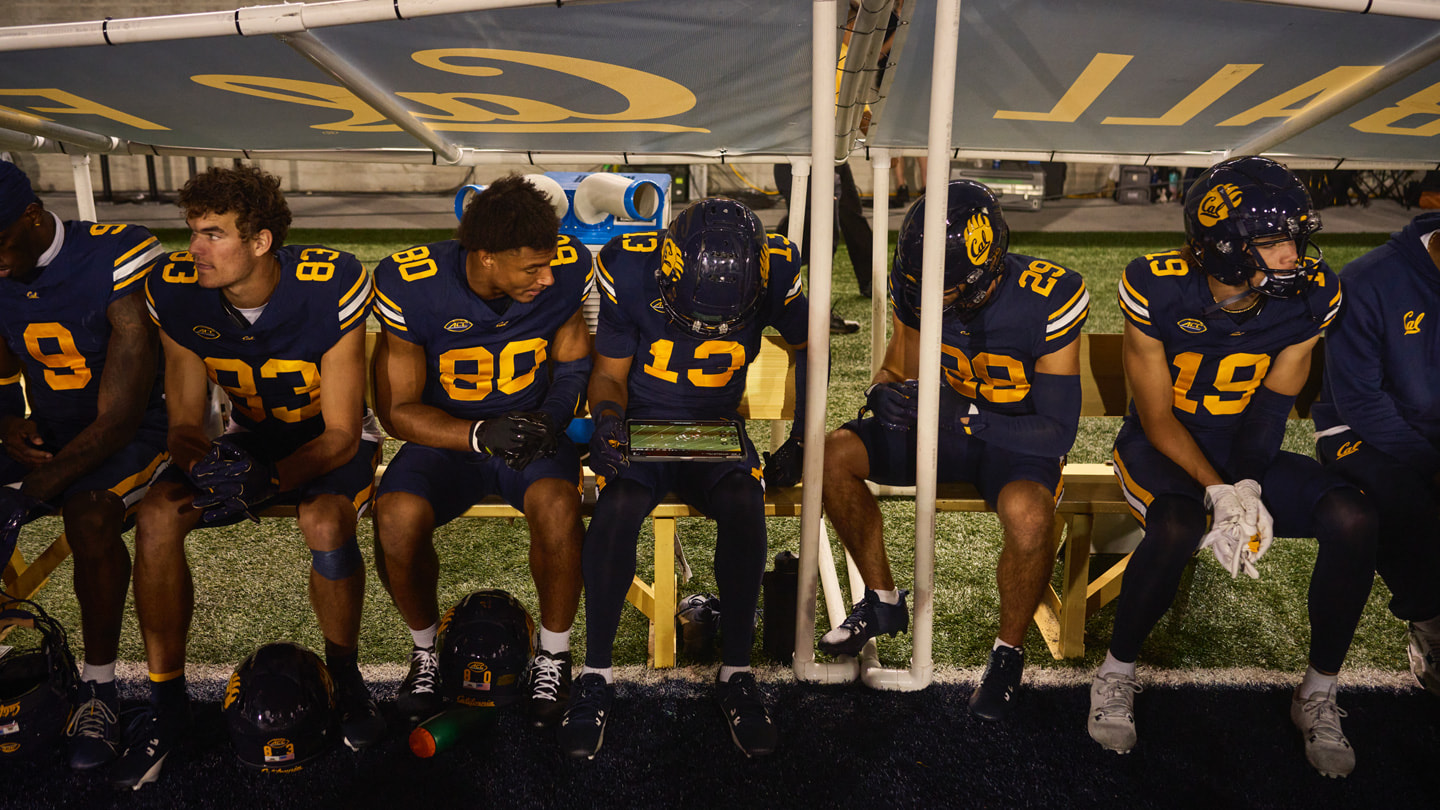 Cal teammates sit on the bench during a football game and review footage on iPad Pro.