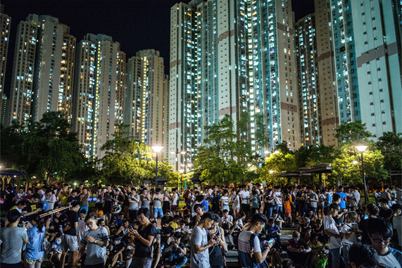 Une foule de personnes jouent à Pokémon Go dans un parc, le soir, à Hong Kong.