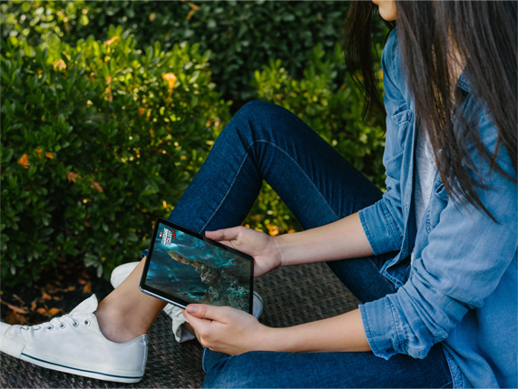 Une femme regarde un film sur iPad à l’extérieur.