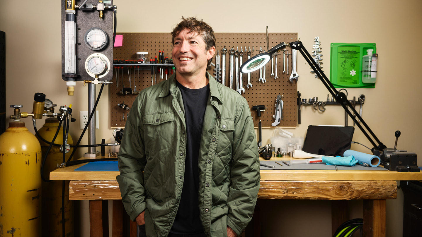 Mike Huish, CEO for Huish Outdoors, står foran en arbeidsbenk med forskjellige verktøy og dykkerutstyr. 
