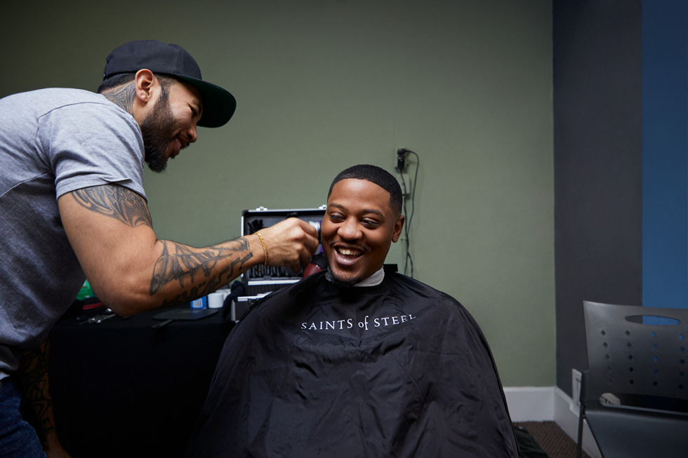 Un coiffeur offre une coupe à un jeune homme.