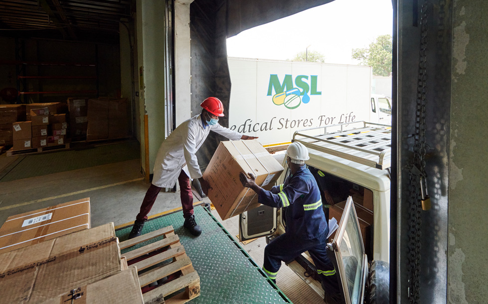 Arbejdere i Zambia ved et lager, der læsser en kasse på et køretøj.