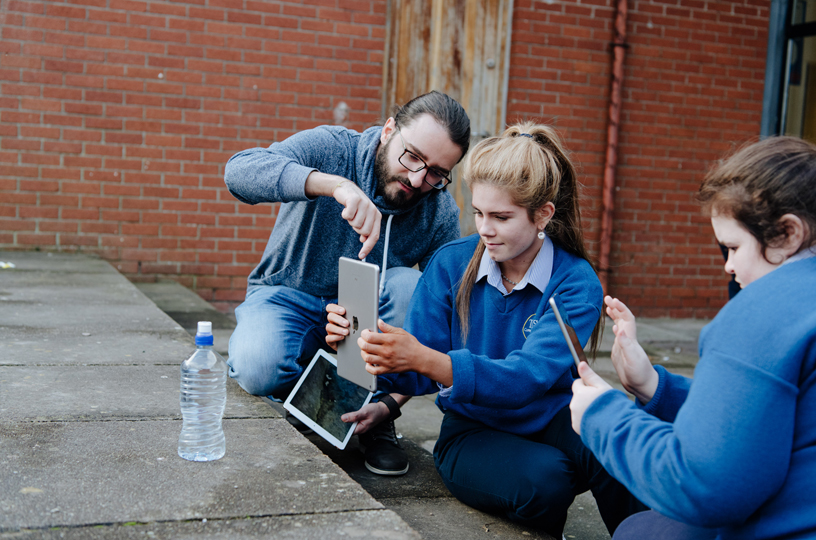 Une jeune femme prend une photo sur iPad avec l’aide d’un bénévole d’Apple.
