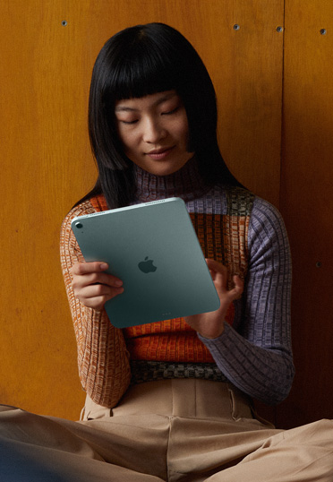 一位學生靠牆坐在地上，手中正持著一部 iPad。