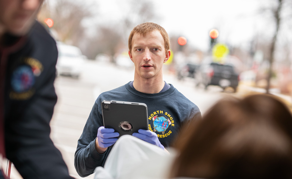 En medarbetare som håller i en iPad talar med en patient i en ambulans