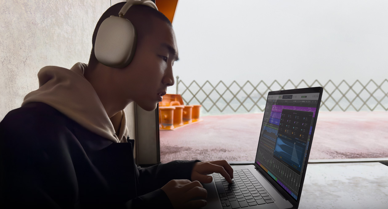 มุมมองด้านข้างของบุคคลหนึ่งที่สวม AirPods Max ขณะใช้ Logic Pro บน MacBook Pro รุ่น 16 นิ้ว