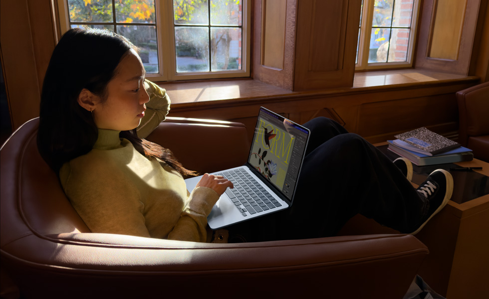 Iemand zit in een fauteuil en werkt op een MacBook Air