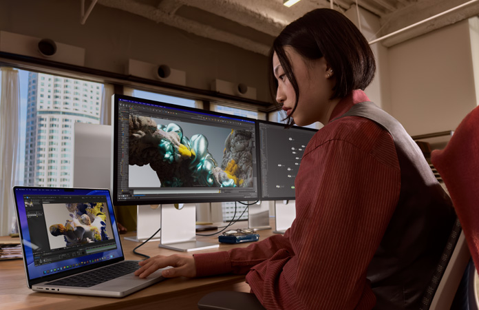 Uma pessoa trabalha em um escritório com um MacBook Pro conectado a um Studio Display XDR